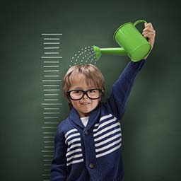 Child pouring water from a watering can on his head to grow.